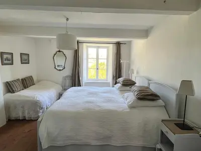 a white bedroom with two beds and a window at Maison vigneronne in Montlaur