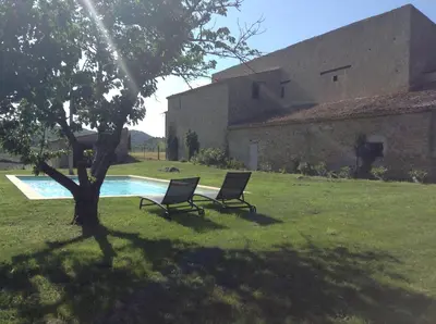 two chairs sitting in the grass next to a pool at Maison vigneronne in Montlaur