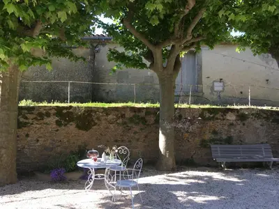 a table and chairs under a tree with a bench at Maison vigneronne in Montlaur