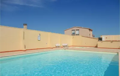 a swimming pool in front of a building with a house at Nice Apartment In Gruissan With Kitchen in Gruissan