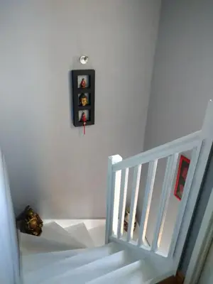 a white staircase with a black clock on the wall at Chambre avec petit déjeuner in Carcassonne