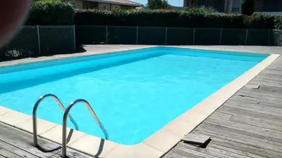 a large blue swimming pool with a wooden deck at Chambre avec petit déjeuner in Carcassonne
