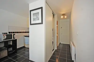 a kitchen with white walls and a black tile floor at Grand studio la Presqu'île 2 in Gruissan