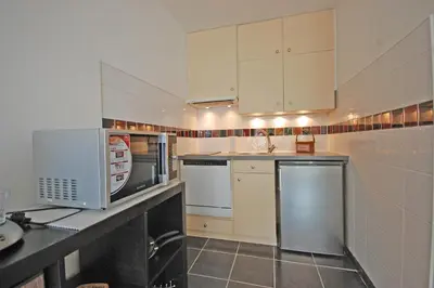 a small kitchen with white cabinets and a microwave at Grand studio la Presqu'île 2 in Gruissan