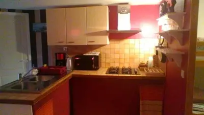 a small kitchen with red cabinets and a sink at Le Refuge in Puivert
