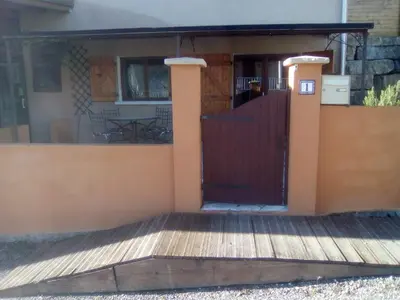 a house with a wooden gate and a patio at Le Refuge in Puivert