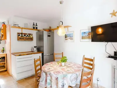 a kitchen with a table and a refrigerator at Pavillon 3 pièces avec Terrasse à Gruissan - 4 Couchages, Animaux Admis, Parking Privé - FR-1-409-31 in Gruissan