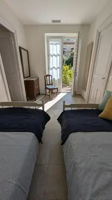 a bedroom with two beds and a chair and a door at Gîte Wistéria in Mazamet