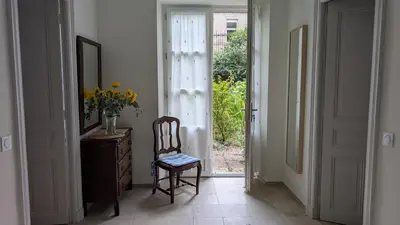 a hallway with a chair and an open door at Gîte Wistéria in Mazamet
