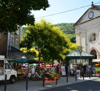an outdoor market with a clock tower and a building at Gîte Wistéria in Mazamet