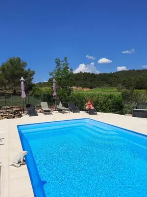 a blue swimming pool with lounge chairs at Gite Charlrose at La Platriere in Cazedarnes