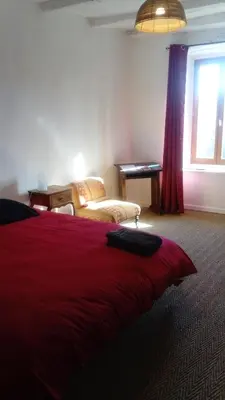 a bedroom with a red bed with a window and a desk at La Bouriotte, chambre d'hôtes Sycomore, in Labastide-Rouairoux