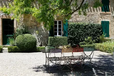 two chairs and a table in front of a building at La Maison Du Village in Val-de-Dagne