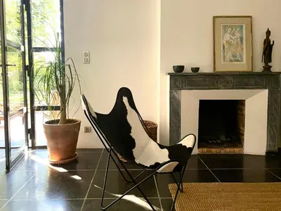 a black chair in a living room with a fireplace at Le Pavillon Du Regisseur in Val-de-Dagne