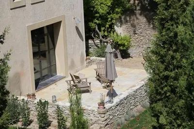 a patio with an umbrella and a chair and a table at Le Pavillon Du Regisseur in Val-de-Dagne
