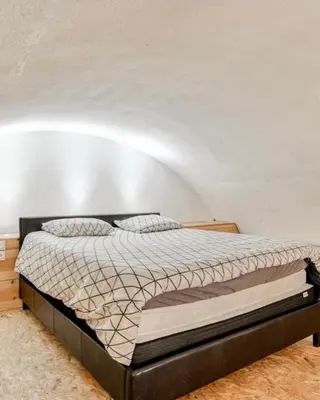 a bed in a room with a white wall at Duplex Climatisé 65m2 refait à neuf in Gruissan