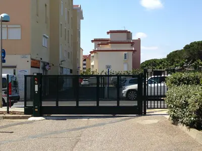 a black gate in front of a parking lot at Duplex Climatisé 65m2 refait à neuf in Gruissan