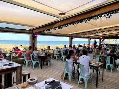 a group of people sitting at tables on a patio with the beach at Duplex Climatisé 65m2 refait à neuf in Gruissan