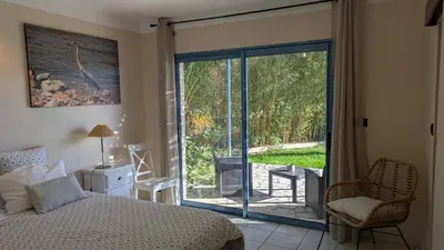 a bedroom with a bed and a sliding glass door at chambres d'hôtes du moulin in Peyriac-de-Mer