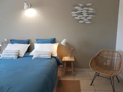 a bedroom with a blue bed and a chair at chambres d'hôtes du moulin in Peyriac-de-Mer