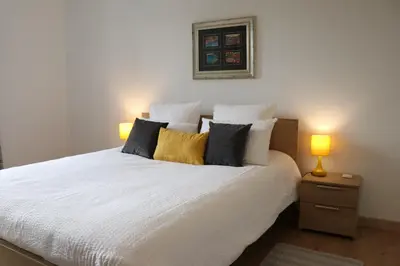 a bedroom with a white bed with two lamps on it at Gîte tout Confort au Coeur du Village Verniolle in Verniolle