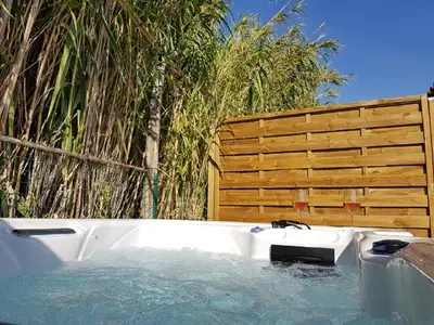 a jacuzzi tub in front of a wooden fence at Gîte Les Roseaux Spa extérieur privatif inclus in Moussan