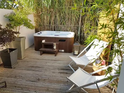a deck with two chairs and a bath tub at Gîte Les Roseaux Spa extérieur privatif inclus in Moussan