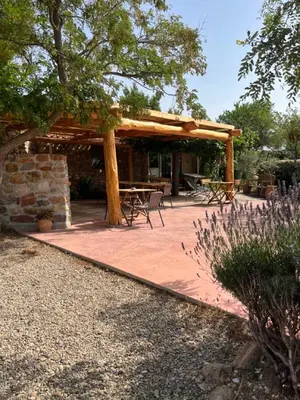 a patio with a wooden pergola and picnic tables at Chambres d'hôtes Gîte Saint Roch in Tuchan