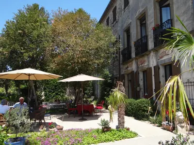 a patio with tables and umbrellas and a building at La Grande Maison in Cambieure