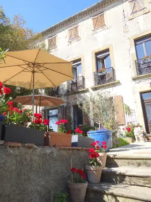 an umbrella and potted flowers in front of a building at La Grande Maison in Cambieure