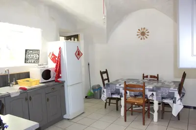 a kitchen with a table and a white refrigerator at Maison près Cité de Carcassonne in Villalier