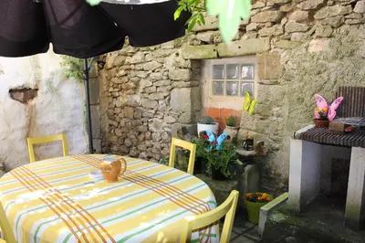 a table and chairs in a room with a stone wall at Maison près Cité de Carcassonne in Villalier