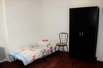 a bedroom with a bed and a chair next to a black cabinet at Maison près Cité de Carcassonne in Villalier