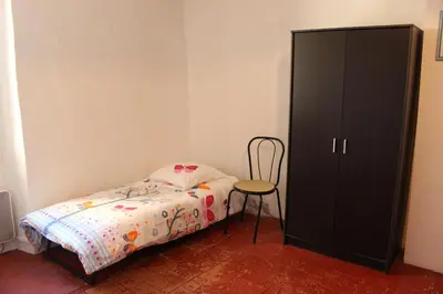 a bedroom with a bed and a cabinet and a chair at Maison près Cité de Carcassonne in Villalier