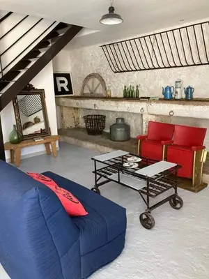 a living room with a blue couch and red chairs at Gîte Chez Les Brocs in Canet d'Aude