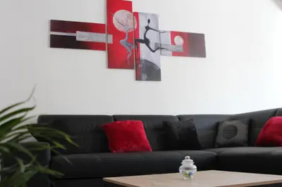 a living room with a black couch and paintings on the wall at Gîte les 3 tours 1e étage in Carcassonne