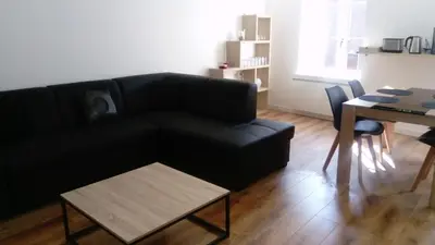 a living room with a black couch and a table at Gîte les 3 tours 1e étage in Carcassonne