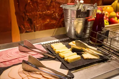 a plate of cheese and utensils on a counter at ibis Carcassonne Centre - La Cité in Carcassonne