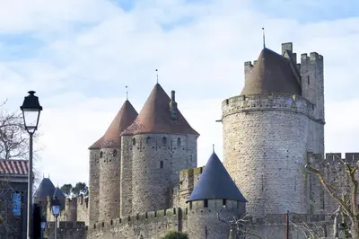 a castle with three towers and a street light at ibis Carcassonne Centre - La Cité in Carcassonne