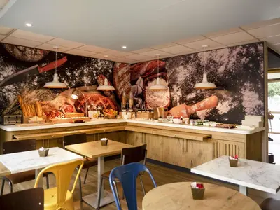 a restaurant with tables and chairs and a wall mural at ibis Carcassonne Centre - La Cité in Carcassonne