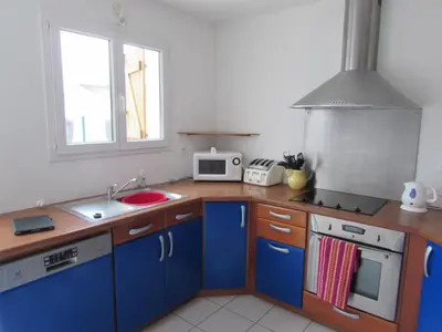 a kitchen with blue cabinets and a sink and a microwave at Maison Minervois in Agel