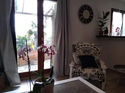 a living room with a chair and a clock on the wall at Gîte avec vue imprenable sur la Cité in Carcassonne