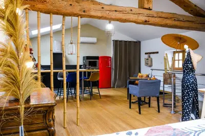 a living room with a table and chairs and a kitchen at L'Autre Jardin, centre historique, calme, garage gratuit in Mirepoix