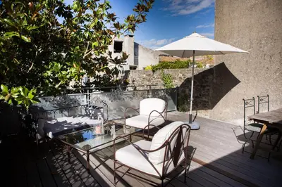 a patio with chairs and a table and an umbrella at L'Autre Jardin, centre historique, calme, garage gratuit in Mirepoix