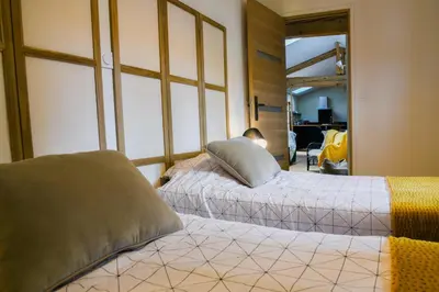a bedroom with two beds and a man sitting in a room at L'Autre Jardin, centre historique, calme, garage gratuit in Mirepoix