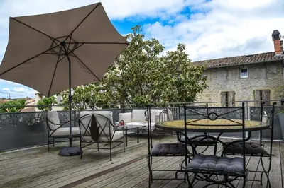 a patio with a table and chairs and an umbrella at L'Autre Jardin, centre historique, calme, garage gratuit in Mirepoix