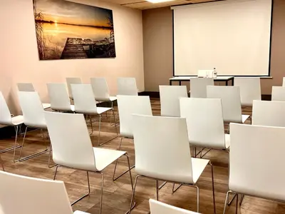 a conference room with white chairs and a whiteboard at The Originals City, Hôtel Le Puech, Narbonne in Narbonne