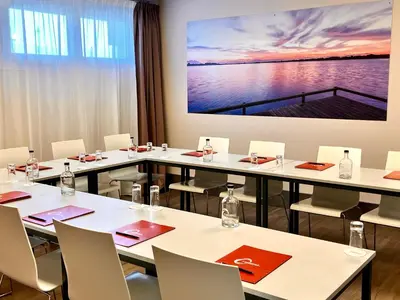 a conference room with tables and chairs and a large screen at The Originals City, Hôtel Le Puech, Narbonne in Narbonne