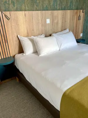 a large bed with white sheets and pillows at The Originals City, Hôtel Le Puech, Narbonne in Narbonne