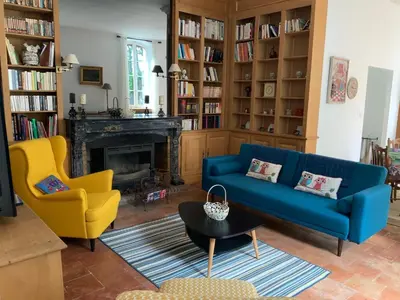 a living room with a blue couch and two yellow chairs at Château Tallavignes in Fabrezan